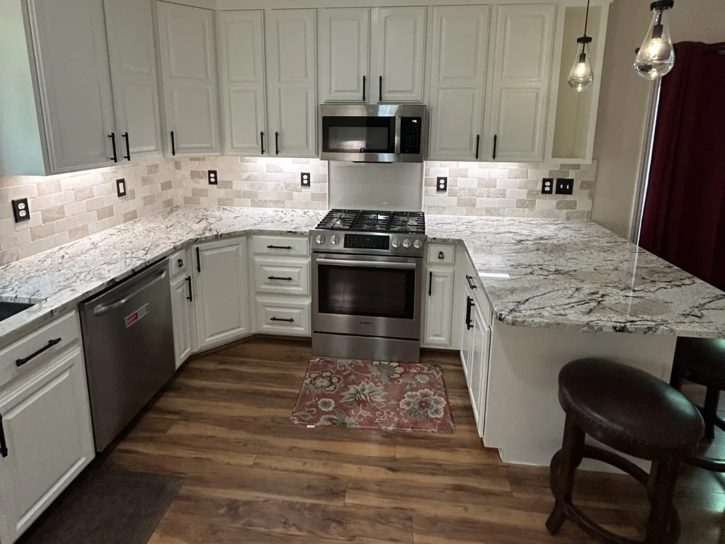 White kitchen cabinets with crown molding, granite counters, stainless range and microwave, and tile backsplash