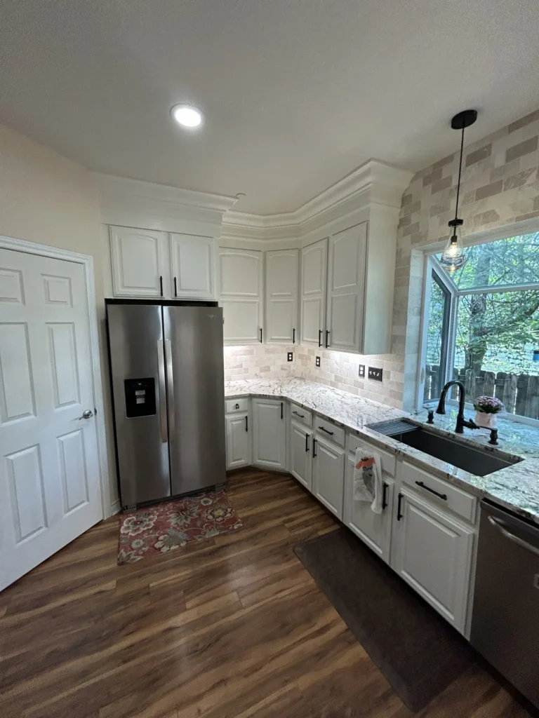 Remodeled kitchen with white cabinets, stainless refrigerator, undermount sink and window over the counter