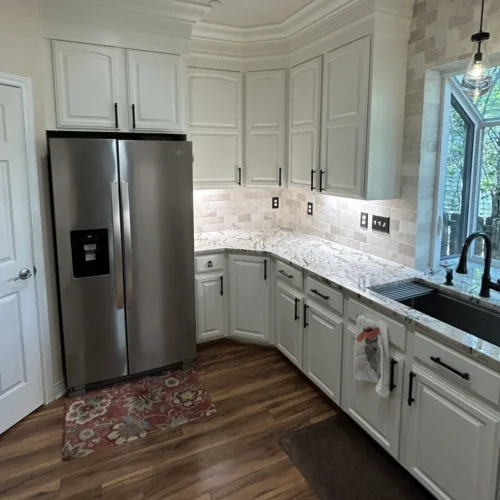 Remodeled kitchen with white cabinets, stainless refrigerator, undermount sink and window over the counter